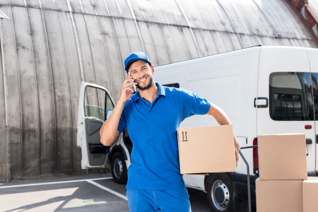 Fahrer eines Transporters mit Karton telefoniert mit Kunden