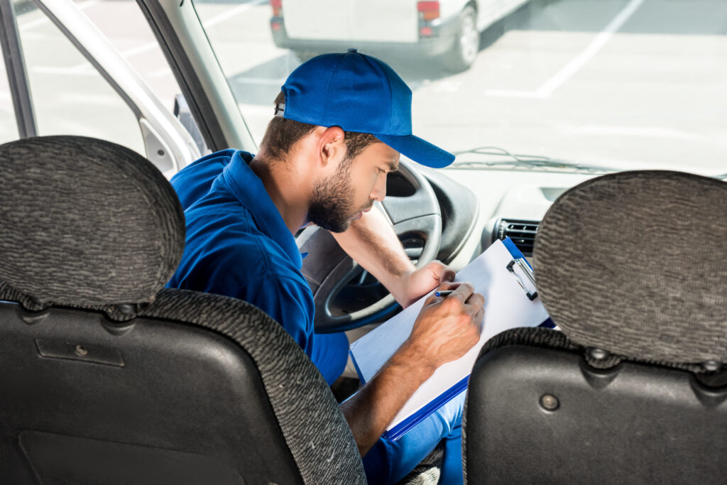 Mitarbeiter in einem Transporter macht sich Notizen für einen Auftrag