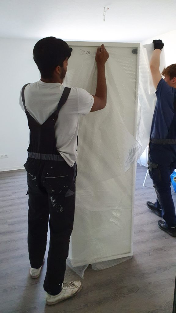 Mitarbeiter verpacken ein Möbelstück in Luftpolsterfolie für besseren Schutz