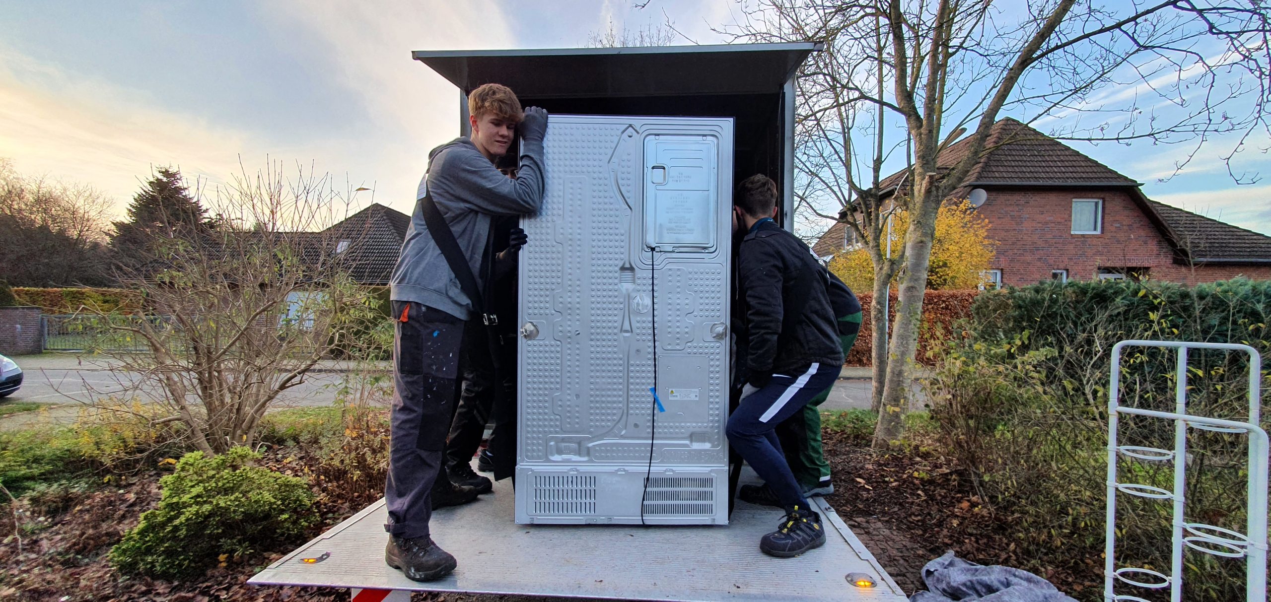 Mitarbeiter von Martens Transport tragen einen Kühlschrank in einen LKW